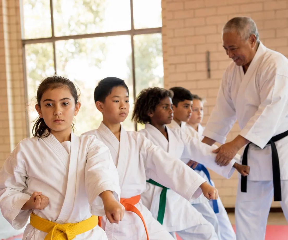 Young martial arts students at a community club session while a coach records their skills for parents/carers to follow